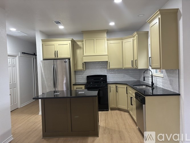 A kitchen with black countertops and wooden floors.