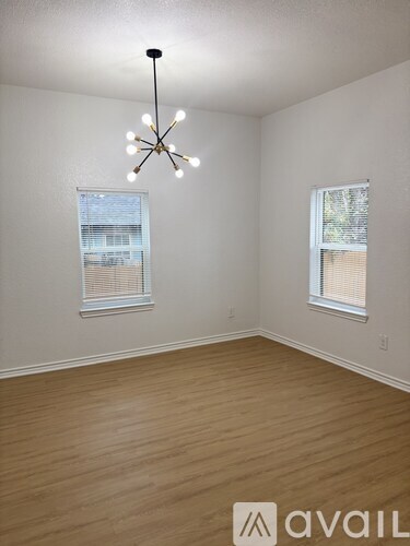 A room with wooden floors and a chandelier hanging from the ceiling.