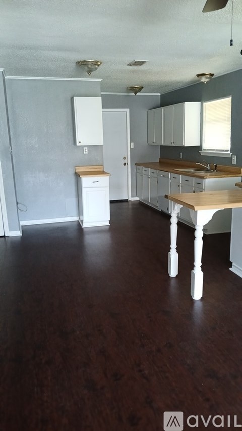 A kitchen with white cabinets and a wooden table.