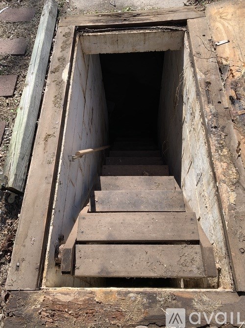 A wooden staircase leads down into a dark hole.