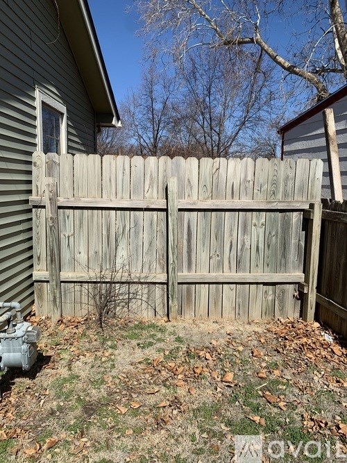 A grey wooden fence in front of a house.