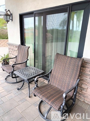 Two chairs and a table are on a patio.