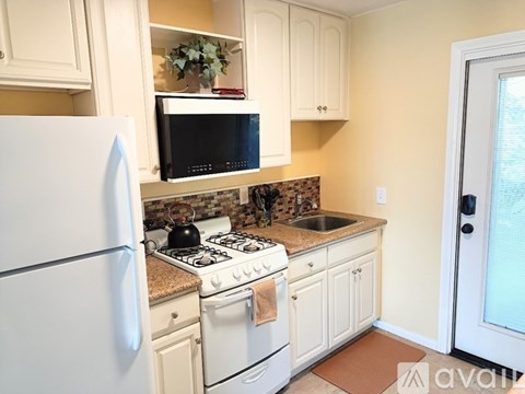 A kitchen with a white refrigerator, a black microwave, and a white stove top oven.