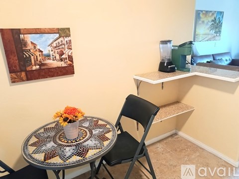A table with a vase of flowers on it and a chair in front of it.