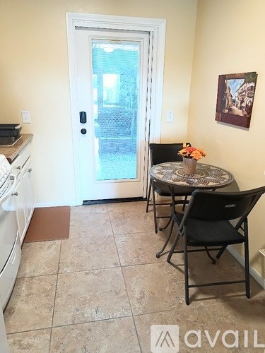 A kitchen with a table and chairs in front of a door.