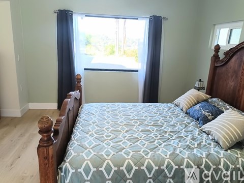 A bed with a blue and white patterned comforter sits in a room with a window.