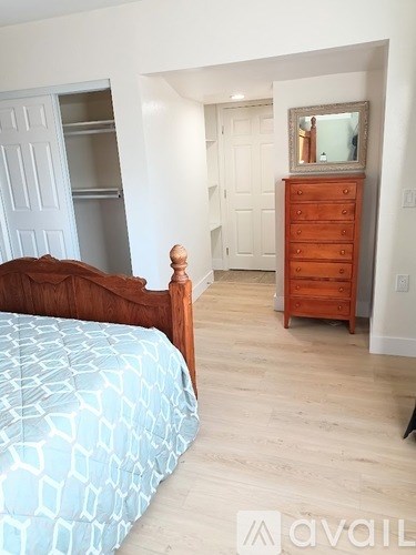 A bedroom with a bed, dresser and mirror.