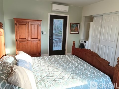 A bedroom with a bed, wooden furniture, and a door leading outside.