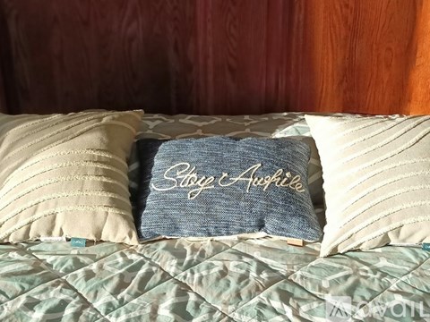 A bed with a blue pillow that says "Stop Aging" on it.