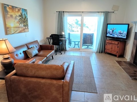 A living room with a brown leather couch and a television on a wooden cabinet.