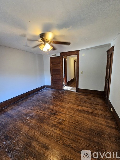 A room with a ceiling fan and wooden flooring.