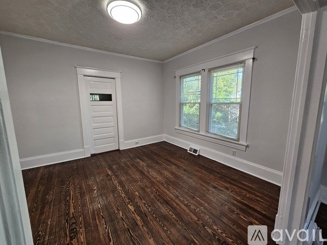 A room with wooden flooring and a window with blinds.