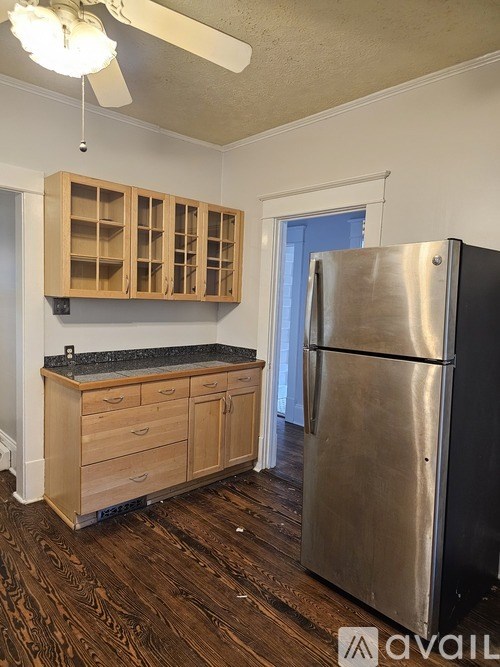 A kitchen with a stainless steel refrigerator and wooden cabinets.