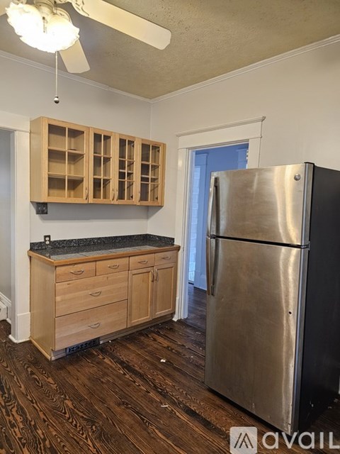 A kitchen with a stainless steel refrigerator and wooden cabinets.