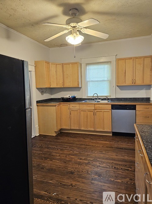A kitchen with wooden floors and a black refrigerator.