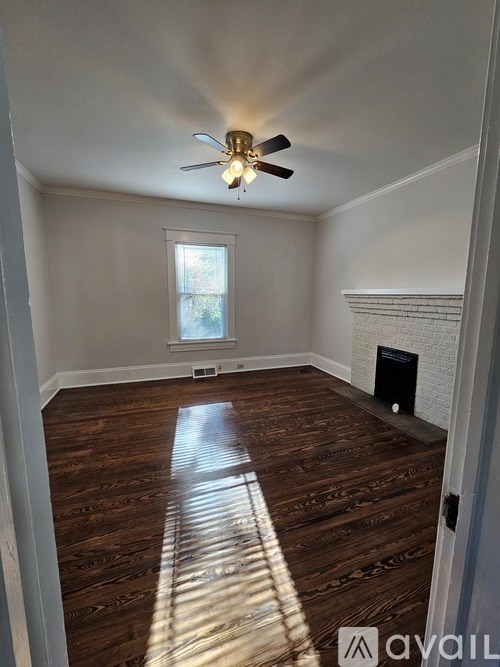 A room with a ceiling fan and wooden flooring.