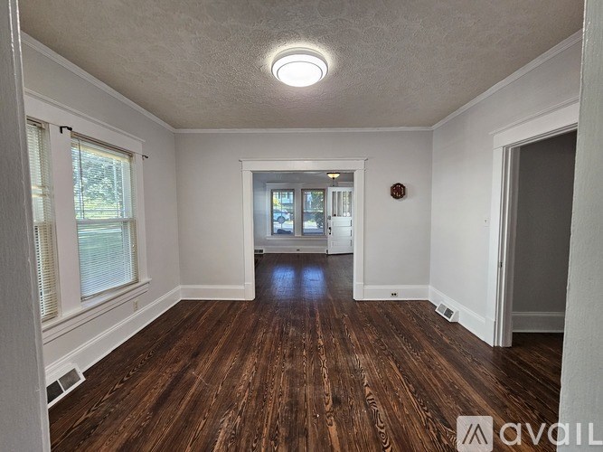 A room with wooden floors and a window on the left side.