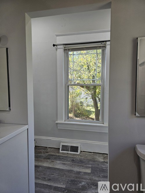 A bathroom with a window and a toilet.