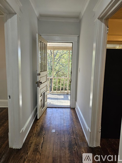 A hallway with wood floors and white walls leading to a balcony.