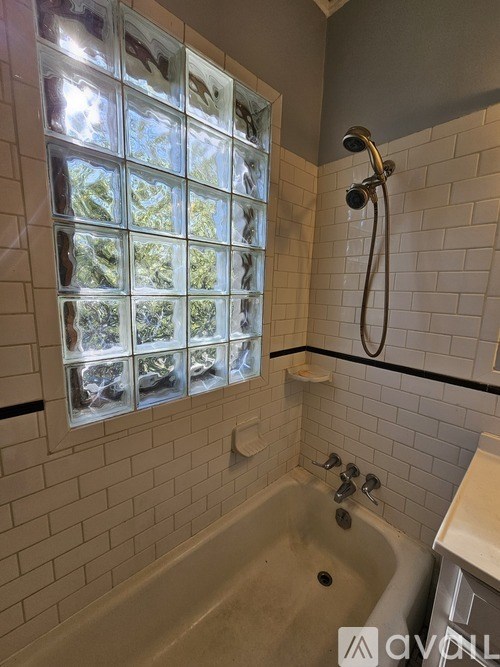 A bathroom with a glass block window in the shower area.