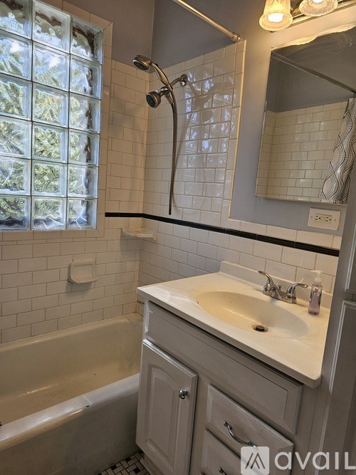 A bathroom with a white sink, bathtub, and a window with a view of trees.