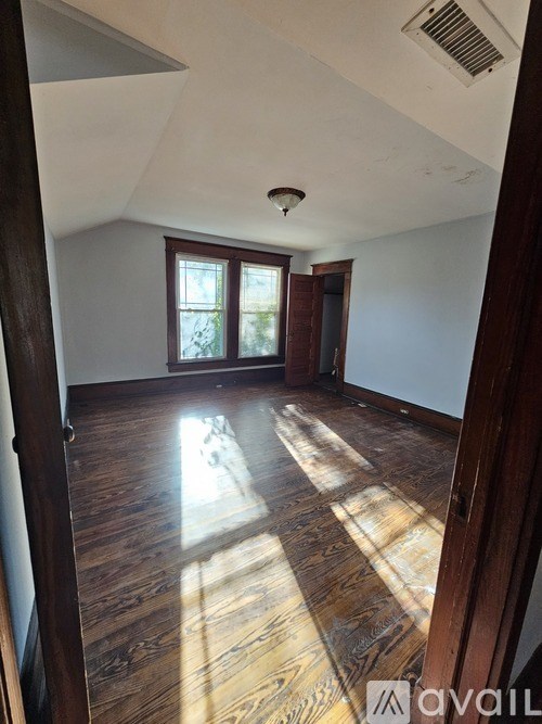 A room with wooden floors and a window letting in sunlight.