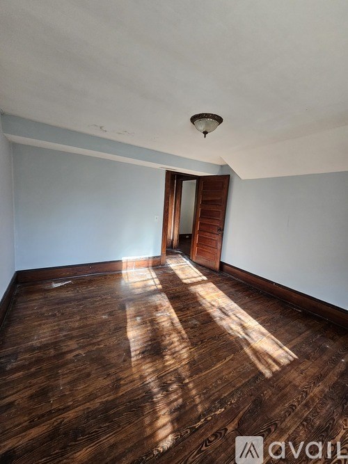 A room with wooden floors and a doorway leading to another room.