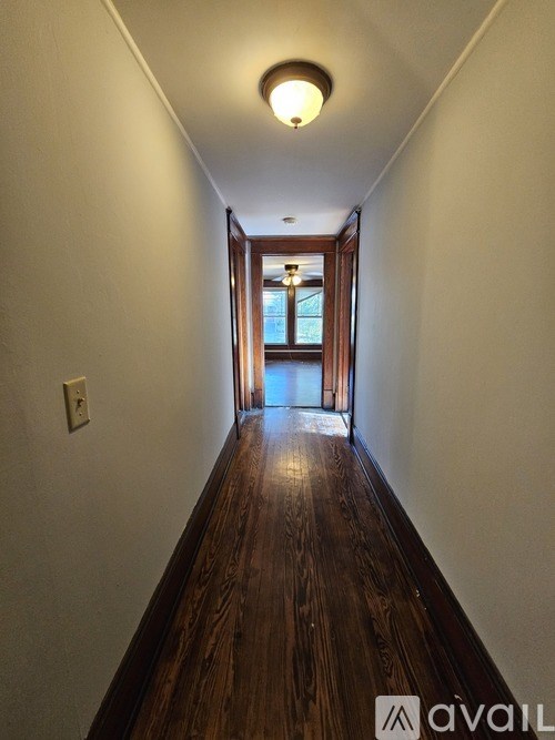 A long hallway with wood floors and a light on the ceiling.