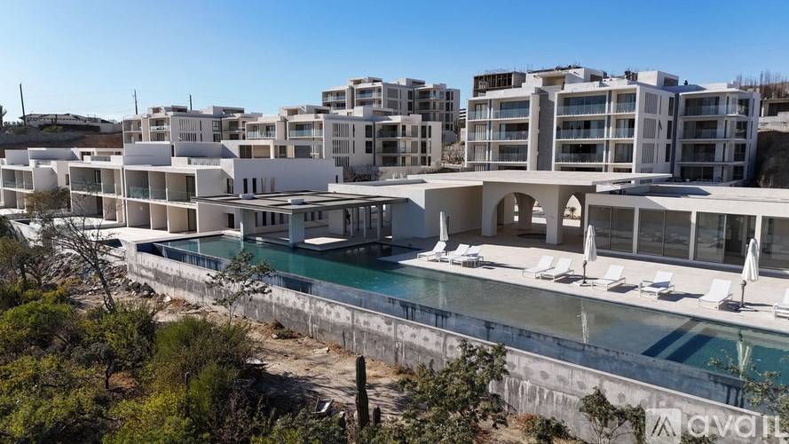A modern building complex with a pool and lounge chairs.