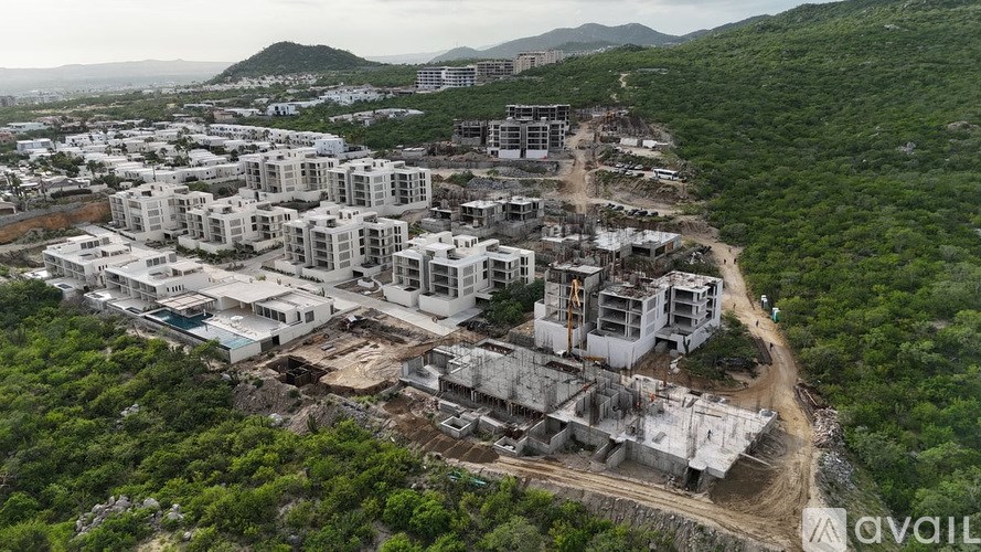 A construction site with multiple buildings under construction surrounded by greenery.