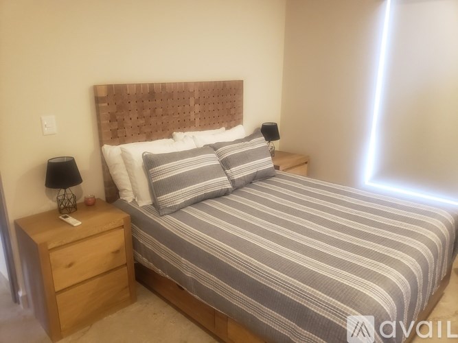 A bedroom with a bed, nightstand, and lamp.