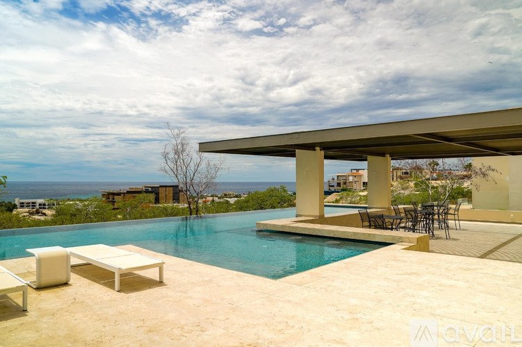 A pool area with a table and chairs under a roof.