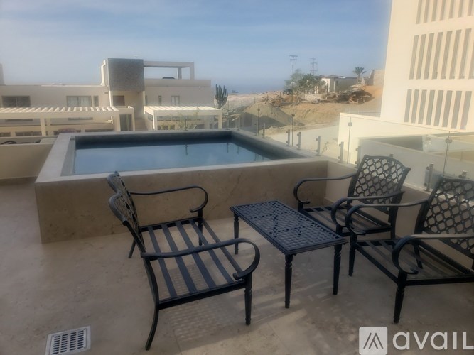 A patio with a table and chairs overlooking the ocean.