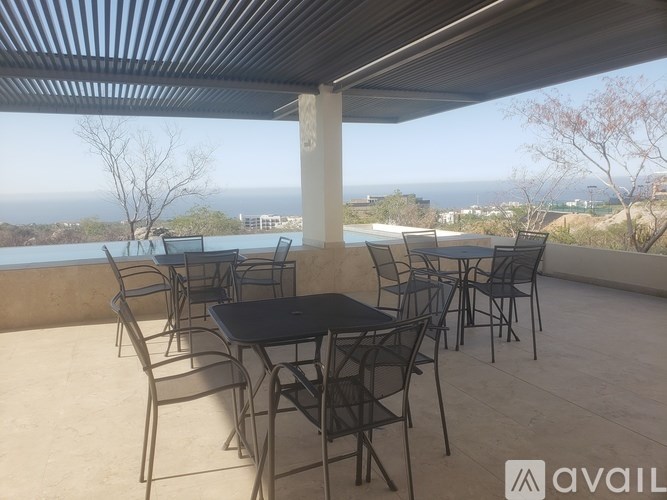 A patio with a table and chairs overlooking the ocean.