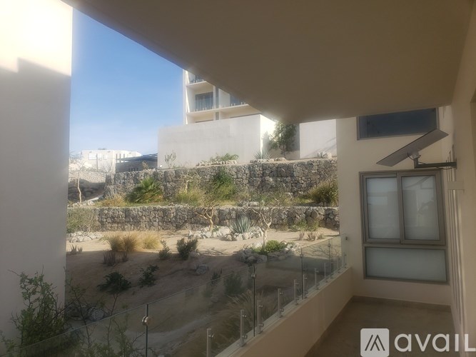 A balcony with a view of a garden and a building.