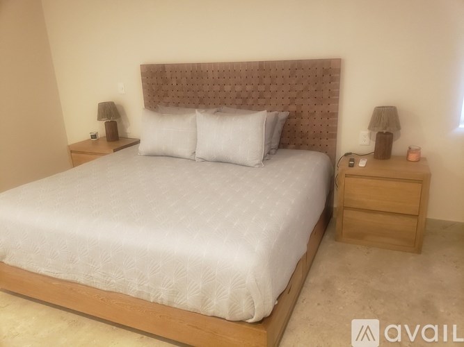 A bed with a white comforter and two white pillows sits in a room with a wooden headboard and nightstands.