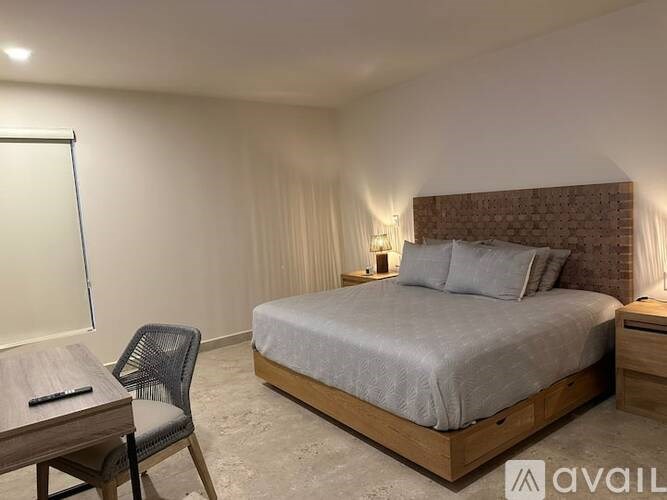 A bedroom with a bed, chair, and lamp.