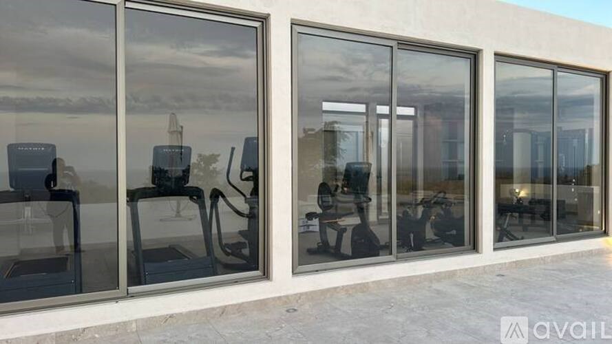 A modern building with large glass windows and a reflection of a building in the background.