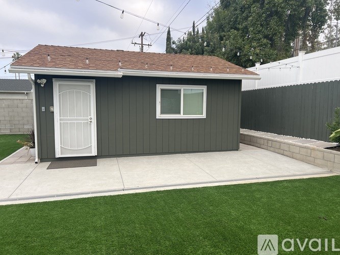 A small house with a grey exterior and a white door is shown.