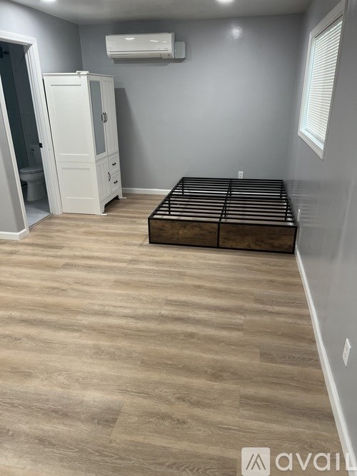 A bedroom with a bed, dresser, and a bathroom with a shower.