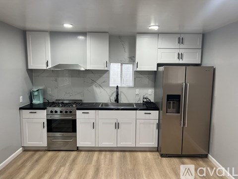 A kitchen with white cabinets and a stainless steel refrigerator.