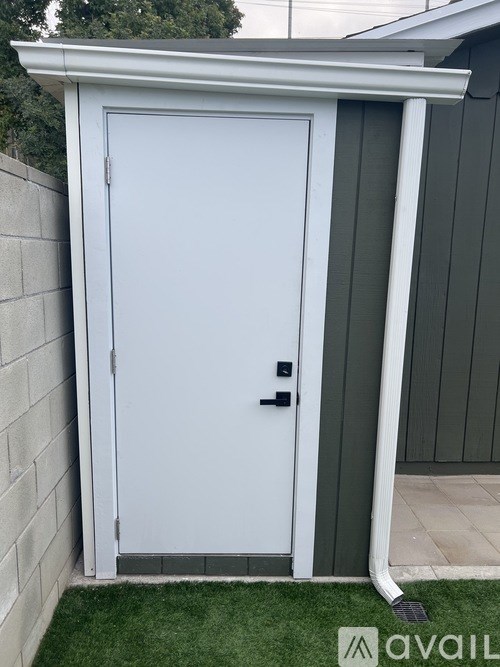 A white door with a black handle is closed and has a small window on the left side.