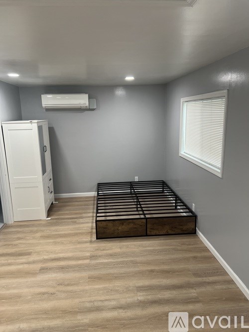 A bedroom with a bed, dresser, and a white refrigerator.