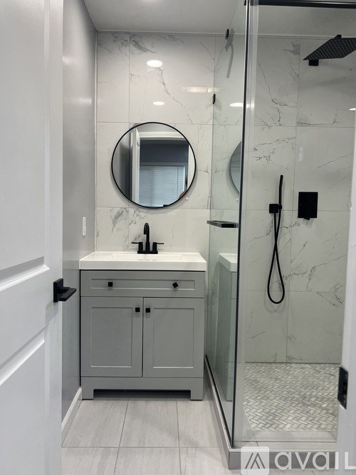 A bathroom with a marble wall and a round mirror above a sink.