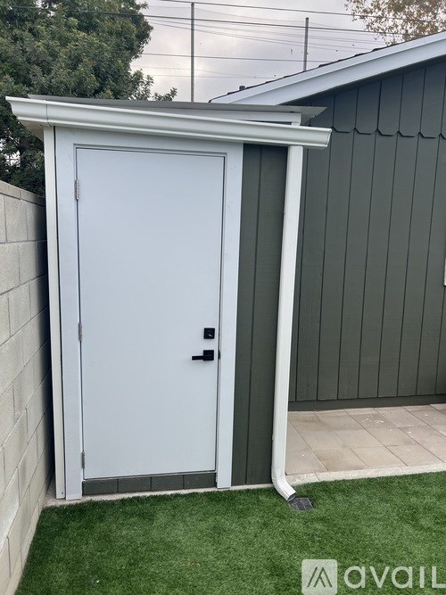 A white door with a black handle is closed and set into a grey wall.