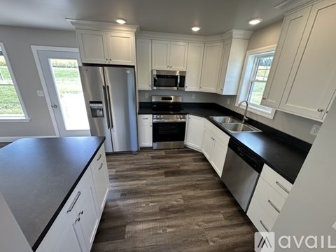 A kitchen with white cabinets and black countertops.