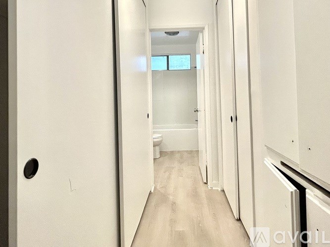 A long hallway with white walls and wood flooring.