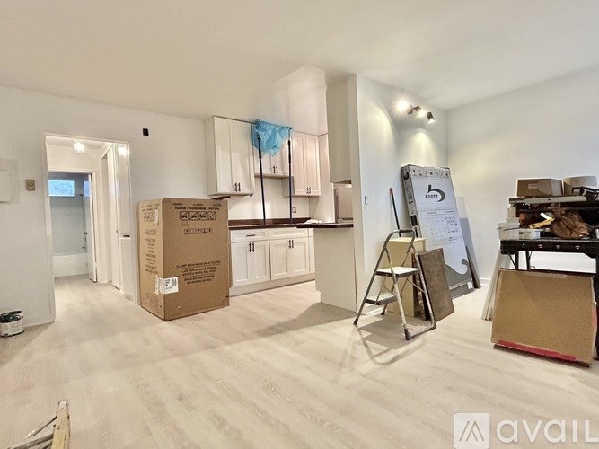 A room with a white floor and walls, with a cardboard box labeled "SCHUMANN" in the foreground.