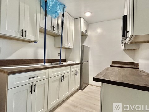 A kitchen with white cabinets and a black countertop is under construction.