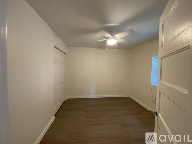 A room with a ceiling fan and wooden flooring.